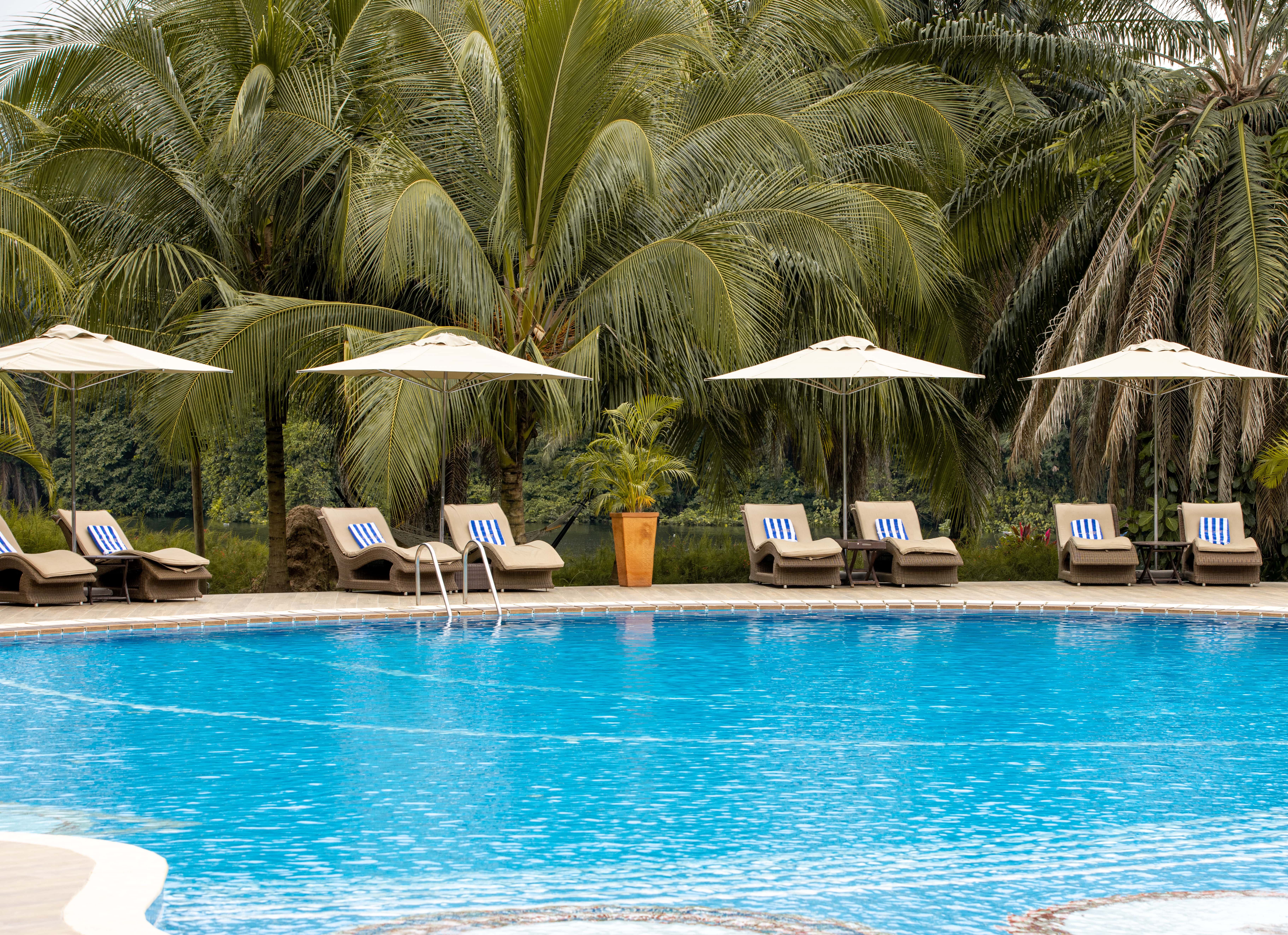 View of the swimming pool and the lounge chairs and beach beds at The Royal Senchi Hotel & Resort, Ghana