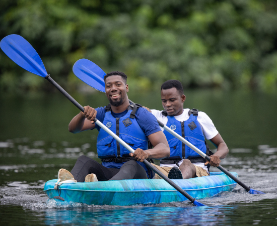 A photo of guests happily kayaking on the Volta River in front of The Royal Senchi Hotel & Resort in Ghana