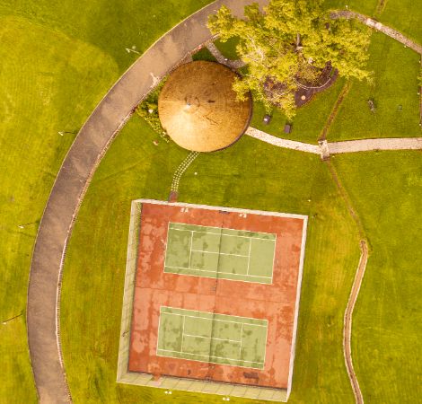 An aerial view of the tennis courts and The Dua Clubhouse and Treehouse at The Royal Senchi Hotel and Resort in Ghana