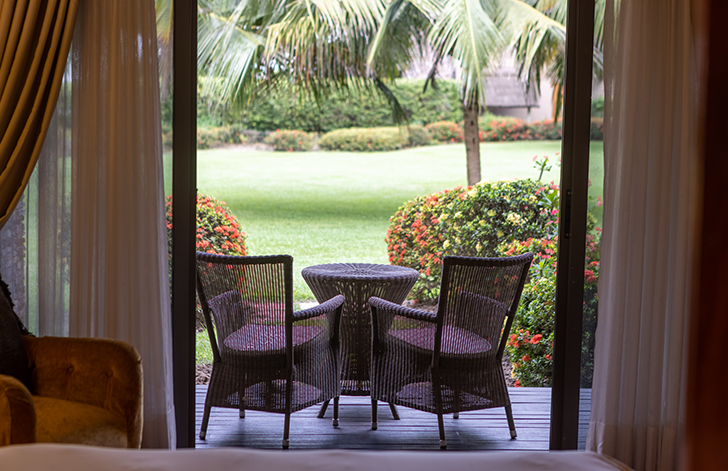 An image of the view of the beautiful garden from the bed in The River View Room at The Royal Senchi Hotel & Resort, Ghana