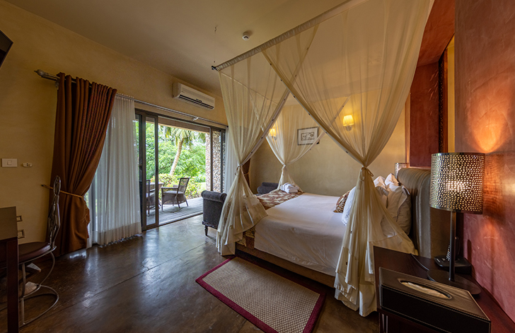 View of the four-poster bed and the views of the garden from The River View Suite at The Royal Senchi Hotel & Resort, Ghana